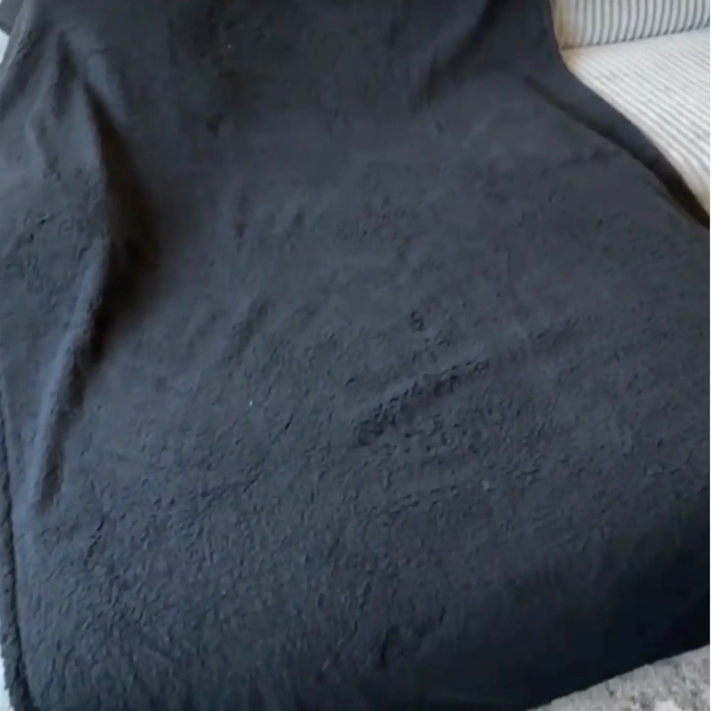 Review with a black LoveBlanket on a couch